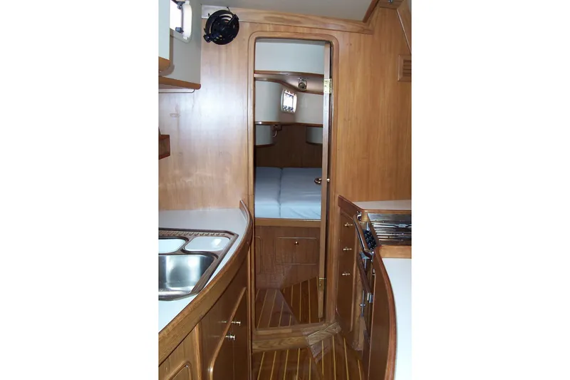 Slide: The Image of Interior of 1994 C&C 51' XL / CB yacht, featuring wooden cabinetry and compact kitchen. - 22