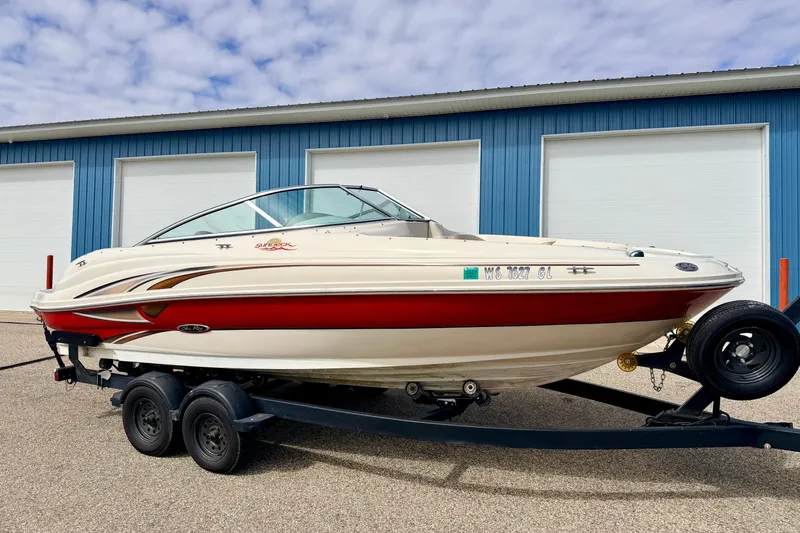 The Image of 2003 Sea Ray 200 Sundeck boat on trailer, parked near blue building. - 0