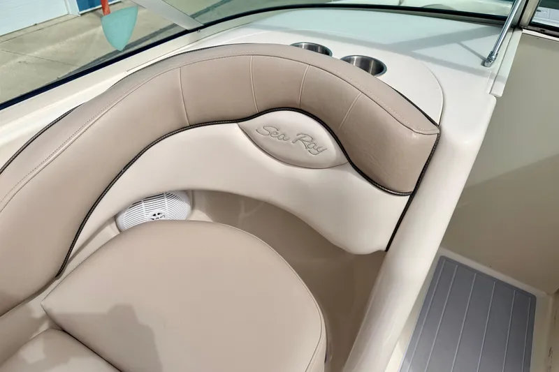 Slide: The Image of 2003 Sea Ray 200 Sundeck interior with beige seating and cup holders. - 26