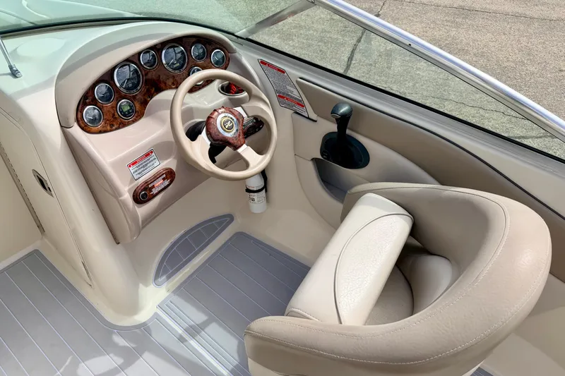 Slide: The Image of 2003 Sea Ray 200 Sundeck helm with gauges, steering wheel, and beige seating. - 27