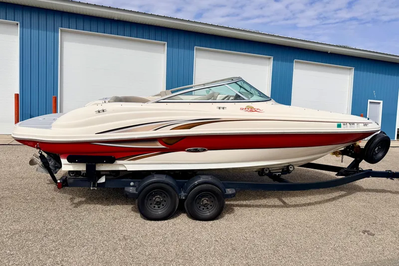 Slide: The Image of 2003 Sea Ray 200 Sundeck boat on trailer, parked outside blue building. - 3