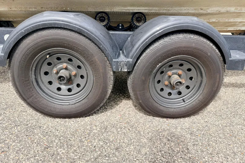 Slide: The Image of Trailer wheels for 2003 Sea Ray 200 Sundeck on asphalt surface. - 4
