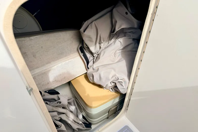 Slide: The Image of Storage compartment in a 2003 Sea Ray 200 Sundeck boat, containing folded fabric and a box. - 41