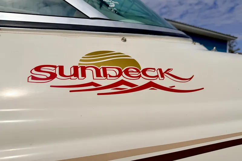 Slide: The Image of 2003 Sea Ray 200 Sundeck logo on boat exterior, featuring sun and wave design. - 6