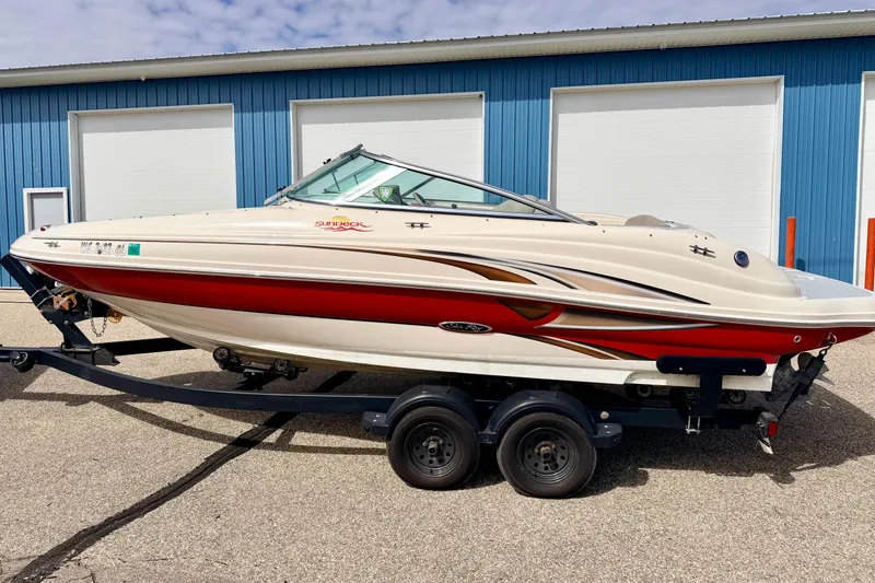 Slide: The Image of 2003 Sea Ray 200 Sundeck boat on trailer, parked near blue building. - 61