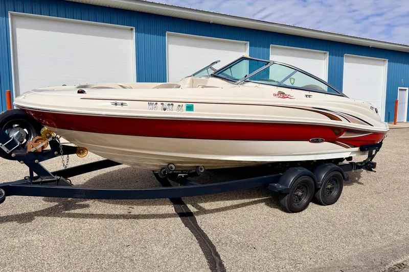 Slide: The Image of 2003 Sea Ray 200 Sundeck boat on trailer, parked outside blue warehouse. - 62