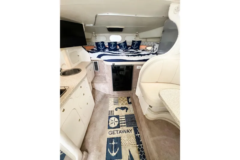 Slide: The Image of Interior of 2000 Rinker Fiesta Vee 330 boat with nautical-themed decor and compact kitchenette. - 19