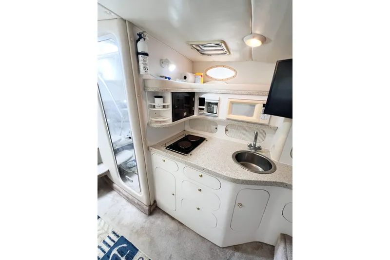 Slide: The Image of 2000 Rinker Fiesta Vee 330 boat interior kitchen with sink, stove, and microwave. - 24