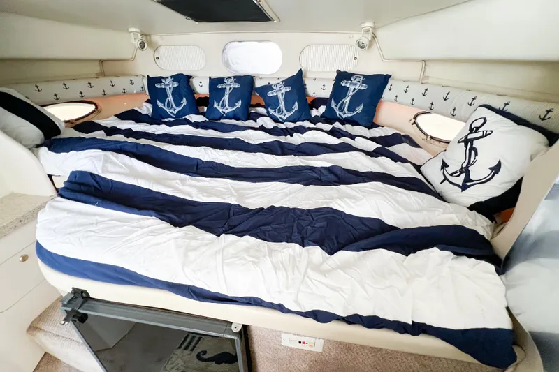 Slide: The Image of Nautical-themed cabin interior of 2000 Rinker Fiesta Vee 330 with anchor pillows and striped bedding. - 38