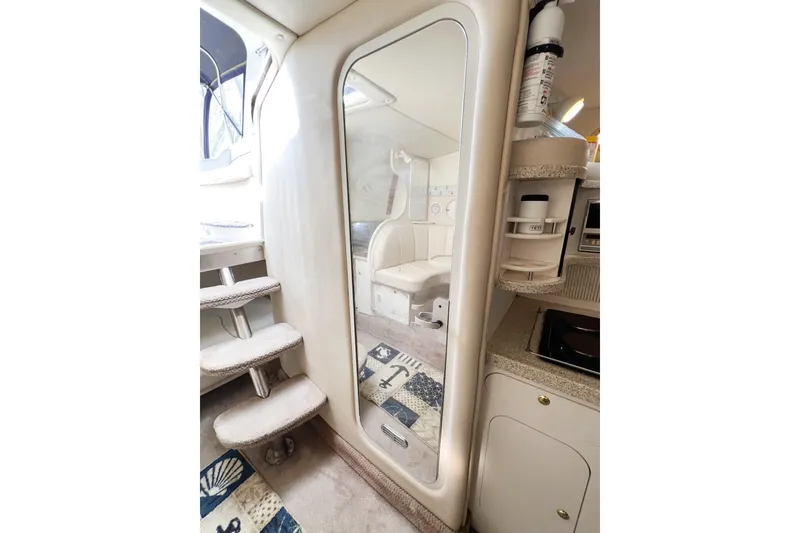 Slide: The Image of Interior of 2000 Rinker Fiesta Vee 330 boat, featuring stairs, mirror, and compact kitchen area. - 41