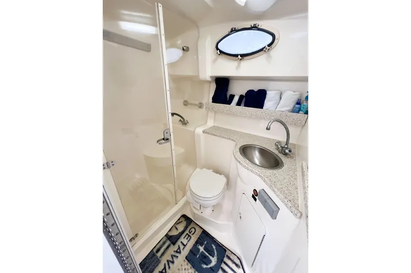 Slide: The Image of Bathroom interior of 2000 Rinker Fiesta Vee 330 boat, featuring sink, toilet, and porthole window. - 43