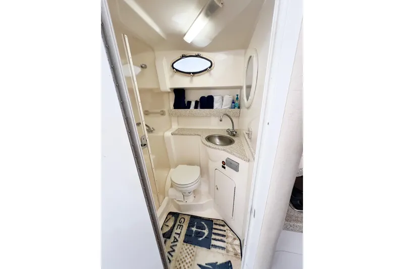 Slide: The Image of Compact bathroom in 2000 Rinker Fiesta Vee 330 boat, featuring sink, toilet, and nautical decor. - 48