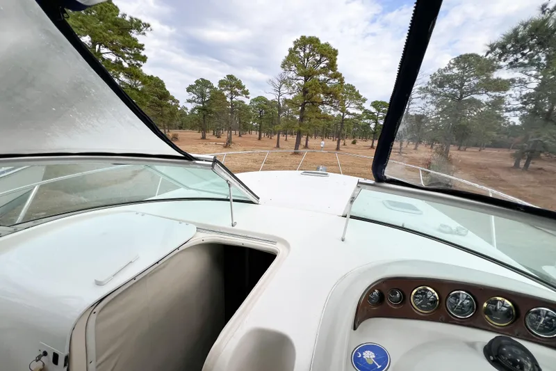 Slide: The Image of Cockpit view of 2000 Rinker Fiesta Vee 330 boat, surrounded by trees under cloudy sky. - 62