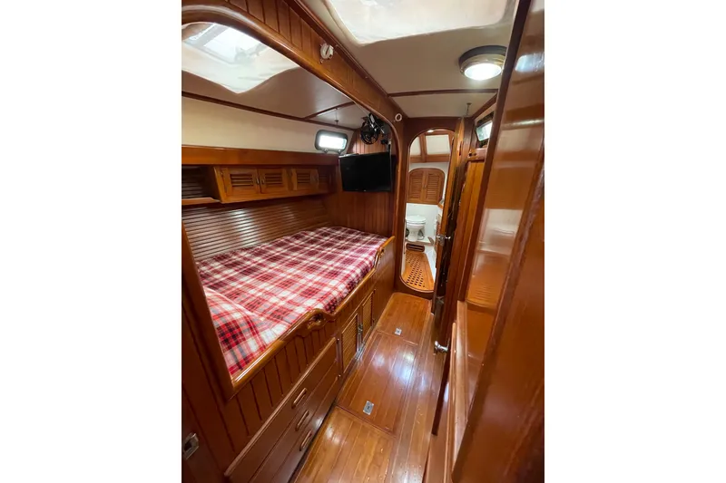 Slide: The Image of Cozy cabin interior of 1985 Passport 470 Center Cockpit with wood paneling and plaid bedding. - 18