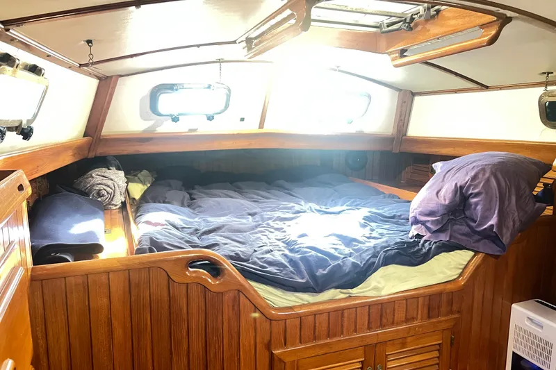 Slide: The Image of Cozy cabin interior of 1985 Passport 470 Center Cockpit sailboat with wooden finish and bedding. - 23