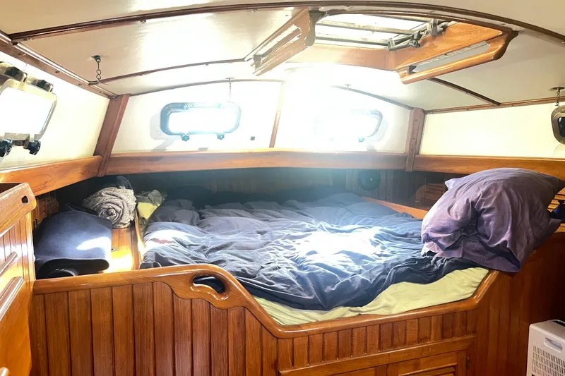 Slide: The Image of Cozy cabin interior of 1985 Passport 470 Center Cockpit sailboat with wooden finish and bedding. - 24