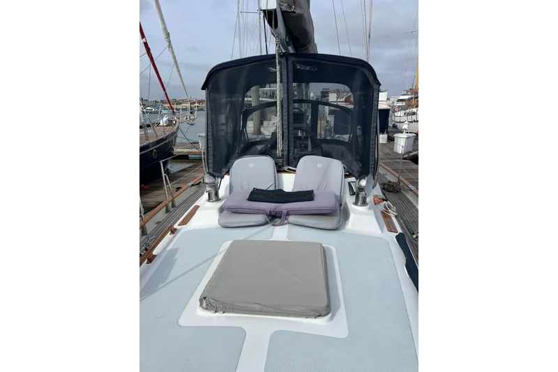 Slide: The Image of 1985 Passport 470 Center Cockpit sailboat with cushioned seating on deck, docked at marina. - 26