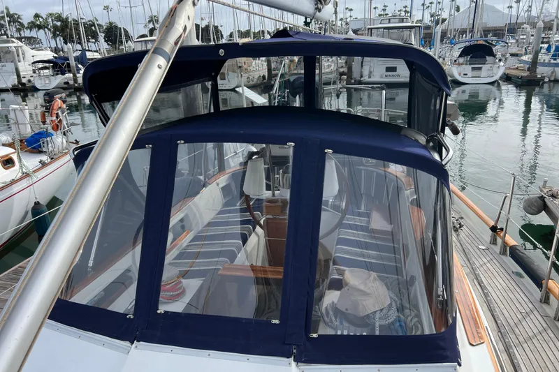 Slide: The Image of 1985 Passport 470 Center Cockpit sailboat docked in a marina, featuring a covered cockpit. - 29