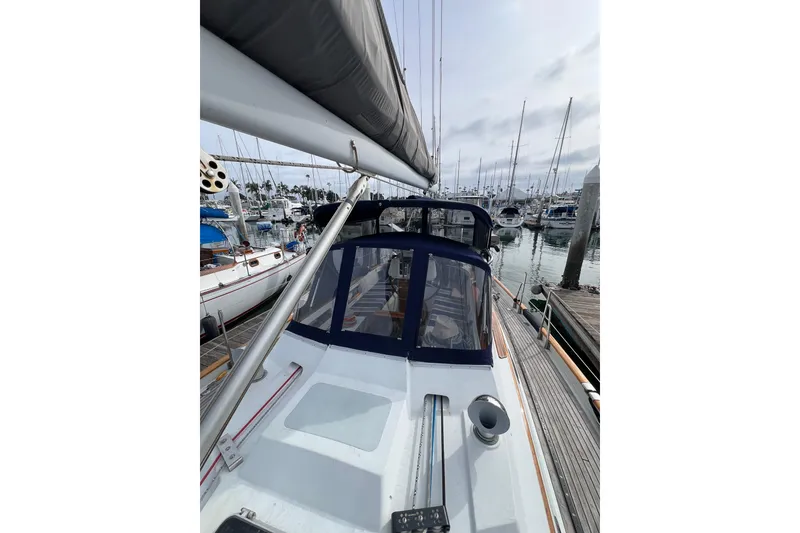 Slide: The Image of 1985 Passport 470 Center Cockpit sailboat docked in a marina, surrounded by other boats. - 30