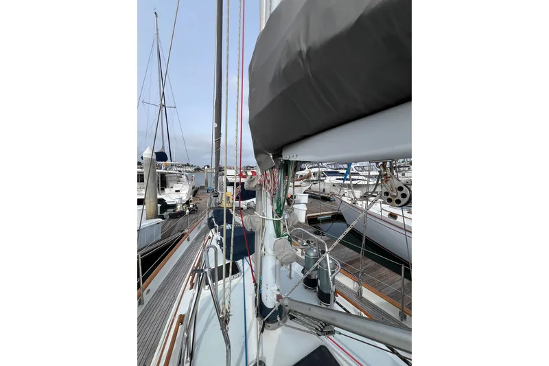 Slide: The Image of 1985 Passport 470 Center Cockpit sailboat docked at marina, showcasing deck and rigging. - 31