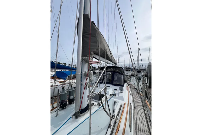 Slide: The Image of 1985 Passport 470 Center Cockpit sailboat docked in marina, showcasing mast and deck. - 33