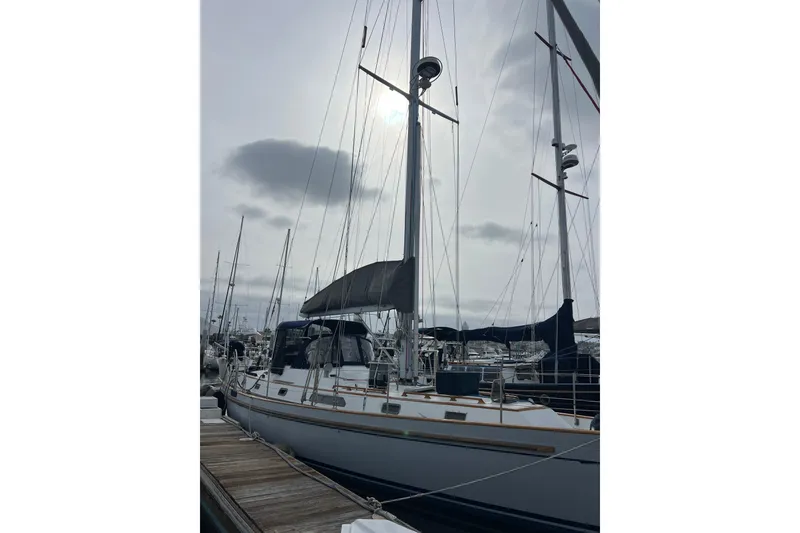 Slide: The Image of 1985 Passport 470 Center Cockpit sailboat docked at marina under cloudy sky. - 44