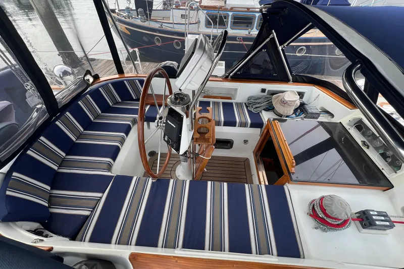 Slide: The Image of Cockpit of 1985 Passport 470 Center Cockpit sailboat with striped seating and wooden steering wheel. - 46