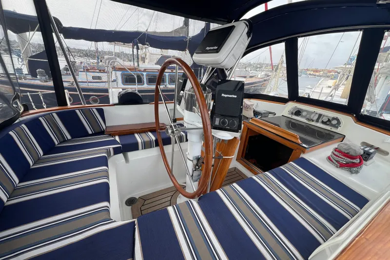 Slide: The Image of 1985 Passport 470 Center Cockpit with striped seating, wooden wheel, and navigation equipment. - 47