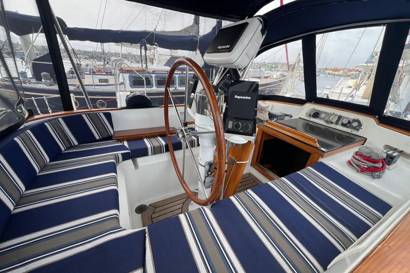 Slide: The Image of 1985 Passport 470 Center Cockpit with striped seating and navigation equipment in marina setting. - 48