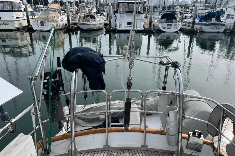 Slide: The Image of 1985 Passport 470 Center Cockpit yacht docked in a marina with surrounding boats. - 50