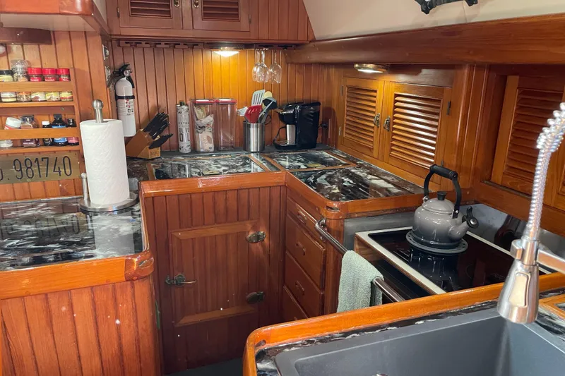 Slide: The Image of Wooden yacht kitchen with marble countertops, stove, and storage in a 1985 Passport 470 Center Cockpit. - 6