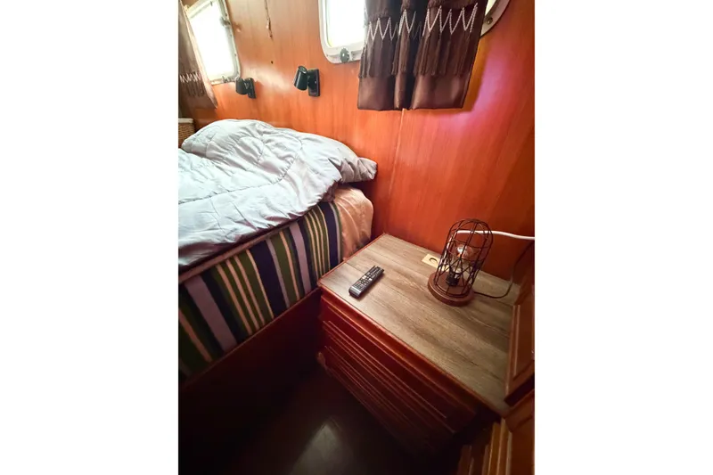Slide: The Image of Cozy cabin interior of 1989 Jefferson Marquessa 52, featuring bed, nightstand, and nautical decor. - 101