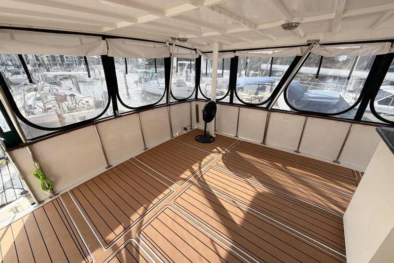 Slide: The Image of Enclosed deck area of a 1989 Jefferson Marquessa 52 yacht with wood-pattern flooring. - 114