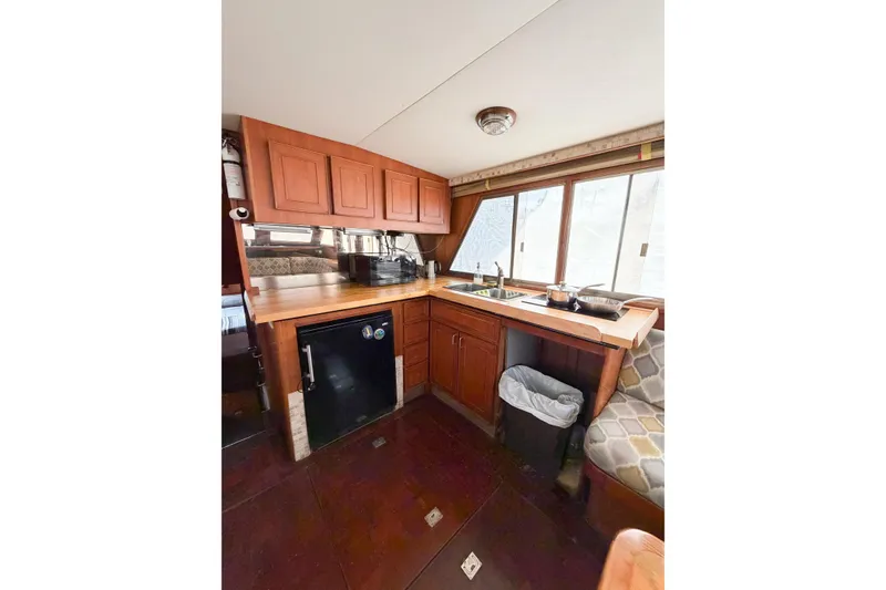 Slide: The Image of 1989 Jefferson Marquessa 52 yacht kitchen with wooden cabinets, sink, and compact fridge. - 64