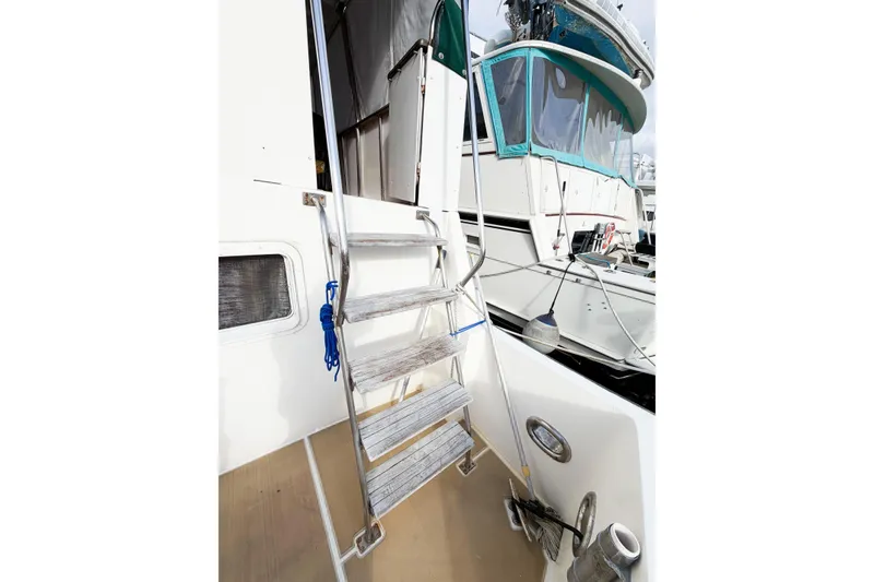 Slide: The Image of Staircase on 1989 Jefferson Marquessa 52 Extended Deckhouse yacht, docked with visible porthole. - 7