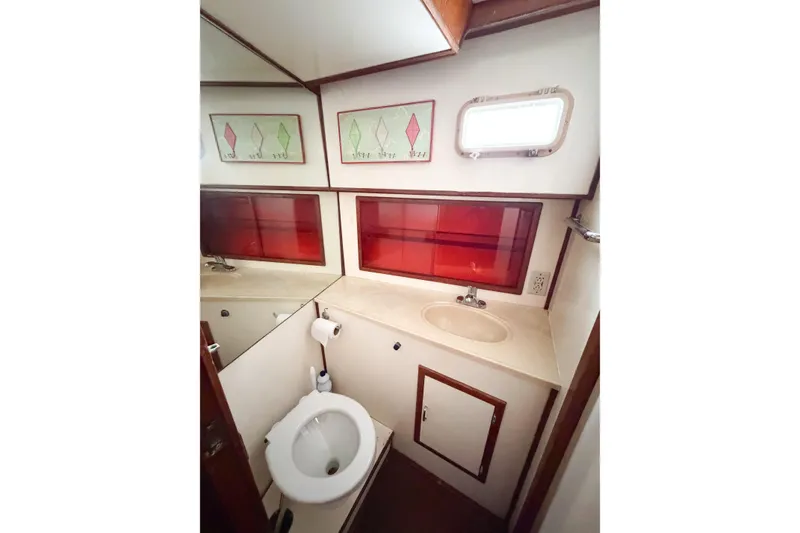 Slide: The Image of 1989 Jefferson Marquessa 52 yacht bathroom with sink, toilet, and red accent panels. - 81