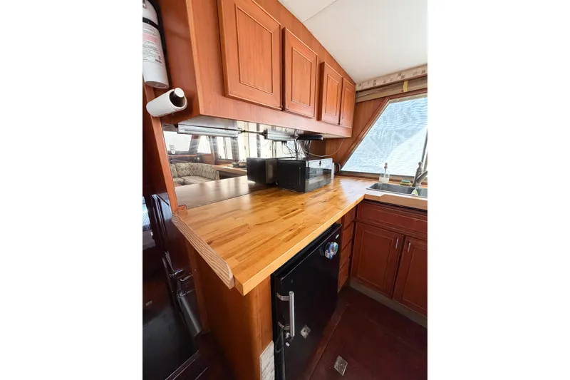 Slide: The Image of 1989 Jefferson Marquessa 52 yacht kitchen with wooden cabinets and countertop, featuring a microwave and sink. - 88