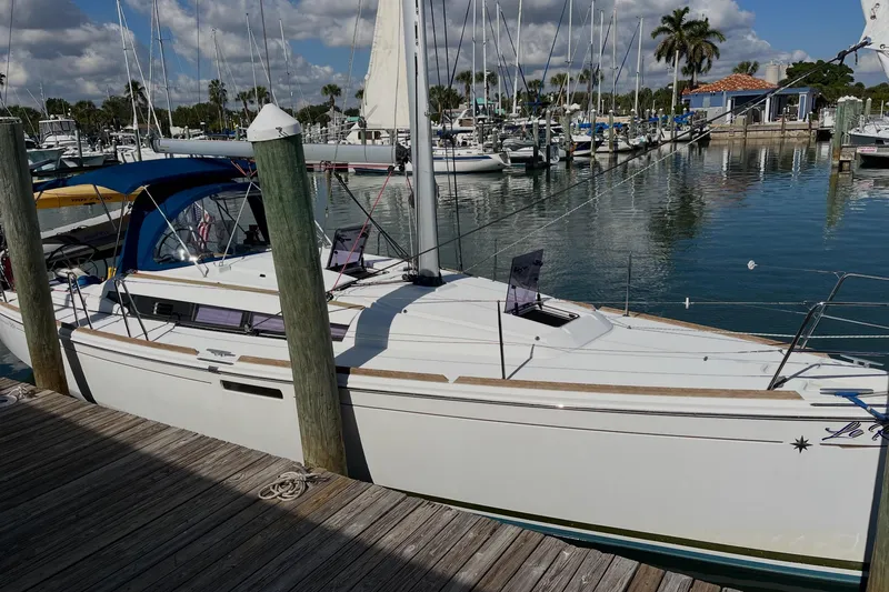 The Image of 2019 Jeanneau Sun Odyssey 389 sailboat docked at a marina under a partly cloudy sky. - 0