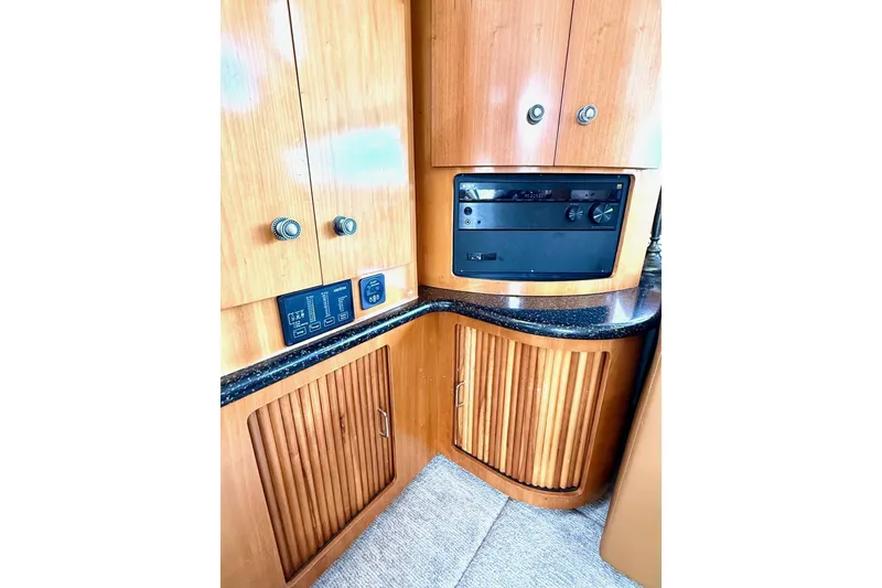 Slide: The Image of 2001 Carver 444 Cockpit Motor Yacht interior with wood cabinetry and black Corian countertop. - 25