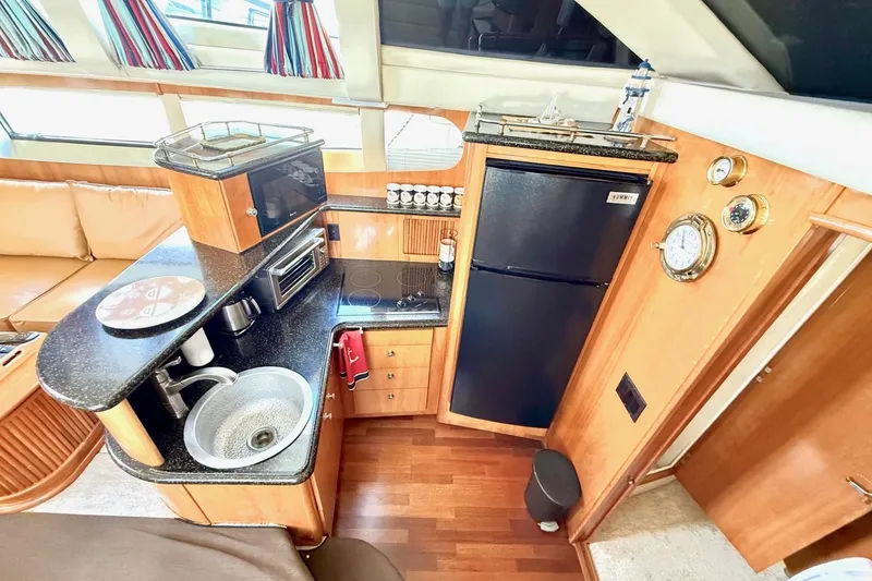 Slide: The Image of 2001 Carver 444 Cockpit Motor Yacht kitchen with sink, microwave, and refrigerator. - 27