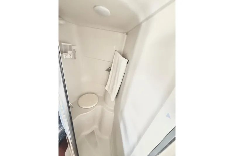 Slide: The Image of Compact shower area in 2001 Carver 444 Cockpit Motor Yacht, featuring white interior and towel rack. - 49