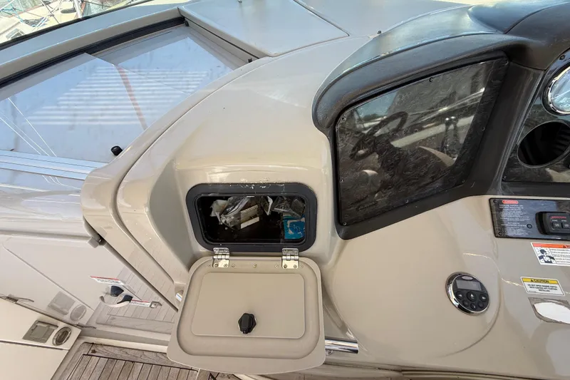 Slide: The Image of 2008 Sea Ray 38 Sundancer helm with open storage compartment and control panel. - 106