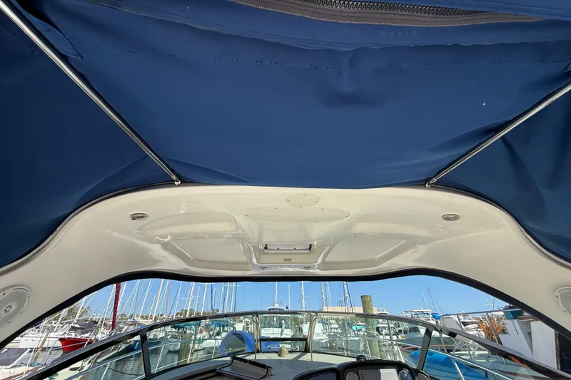 Slide: The Image of 2008 Sea Ray 38 Sundancer cockpit view with blue canopy and marina background. - 27