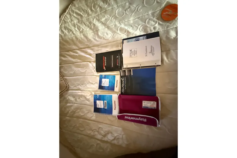 Slide: The Image of Manuals and booklets for 2008 Sea Ray 38 Sundancer on a quilted bedspread. - 45