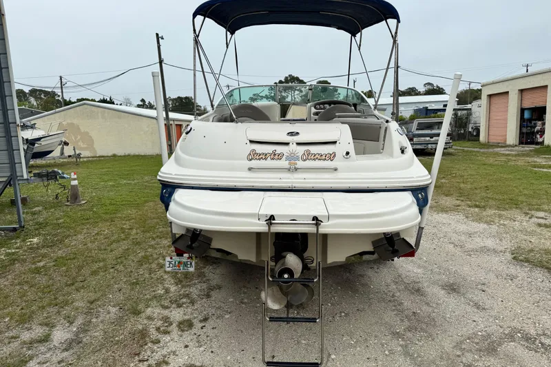 Slide: The Image of 2003 Sea Ray 240 Sundeck boat with canopy, parked on grassy area near storage buildings. - 3
