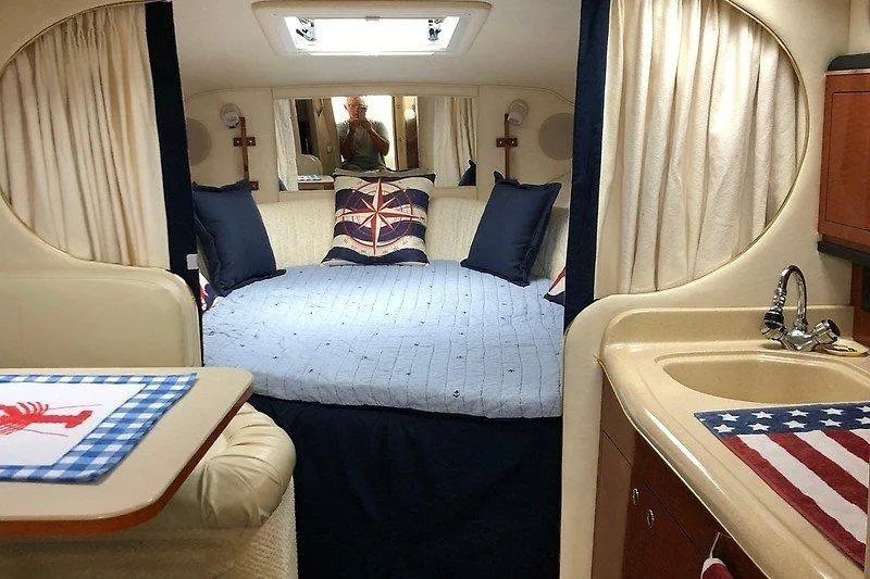 Slide: The Image of Interior of 2001 Sea Ray 290 Sundancer with cozy bed, nautical decor, and kitchenette. - 4