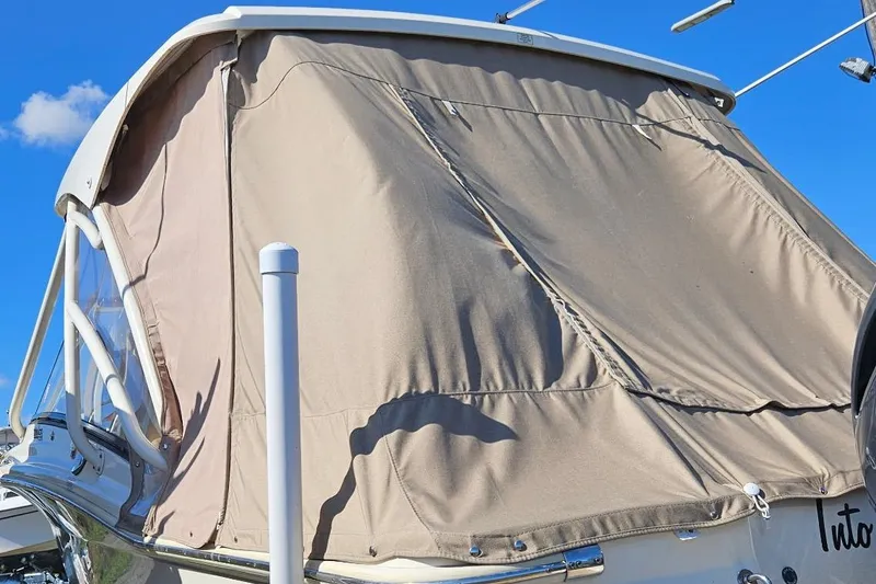 Slide: The Image of 2020 Scout 255 Dorado boat with protective canvas cover under clear blue sky. - 9