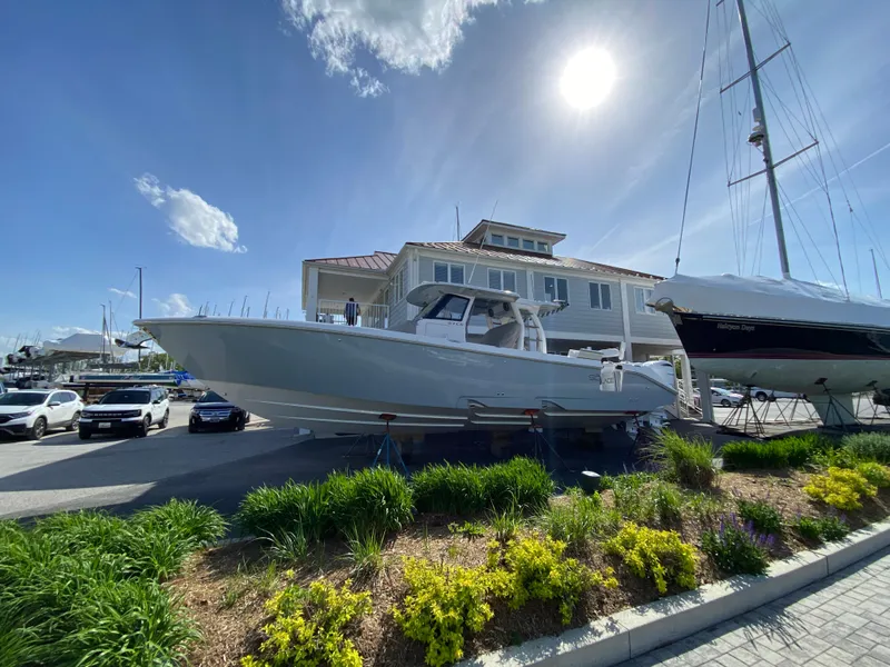 The Image of 2025 Solace 37 CS boat displayed outdoors under bright sun near a marina. - 0