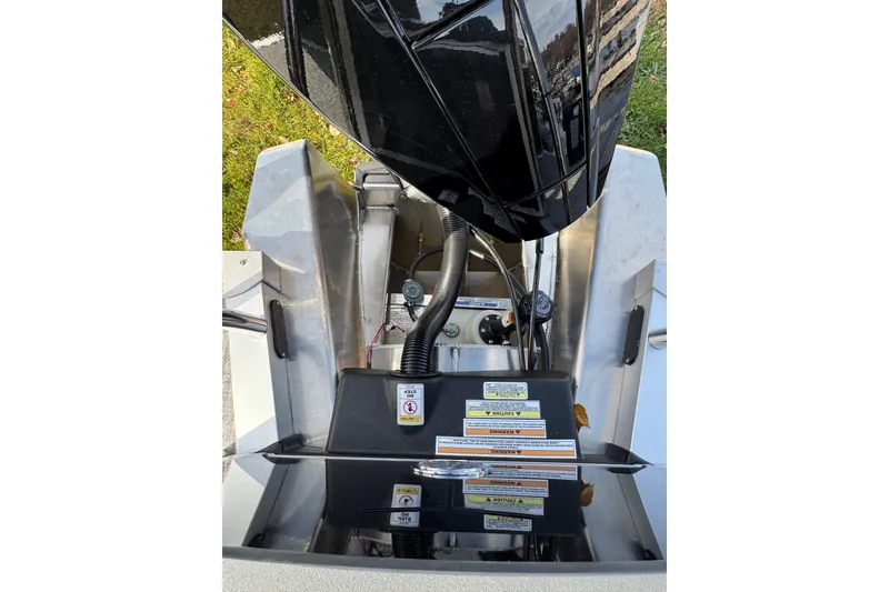 Slide: The Image of 2026 Tahoe Pontoon LTZ Quad Lounger 23 engine compartment with visible warning labels. - 12