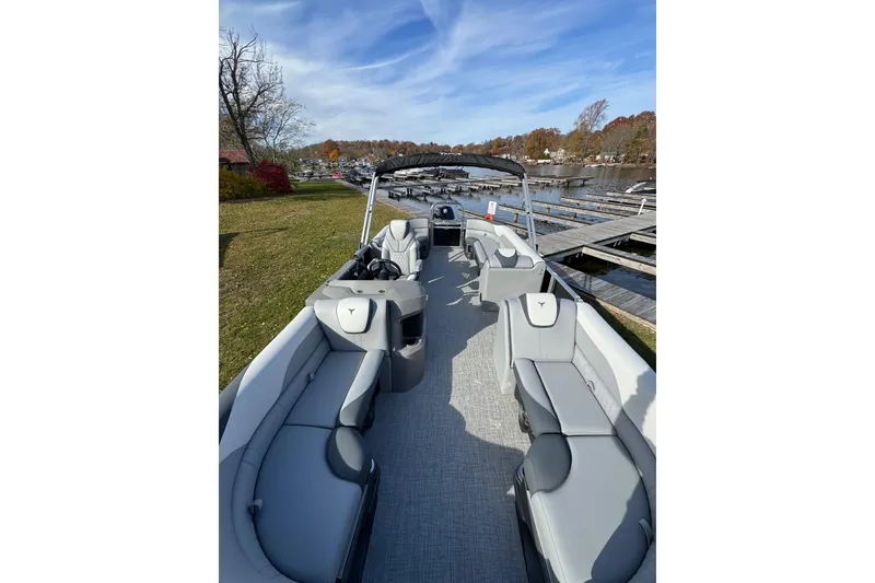 Slide: The Image of 2026 Tahoe Pontoon LTZ Quad Lounger 23 docked by a scenic lakeside. - 2